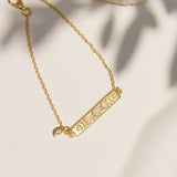 Gold bracelet with a bar design and moon phases on a neutral background