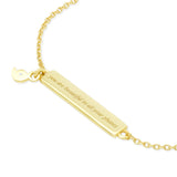 Gold bracelet with a bar pendant and quote engraving on a white background