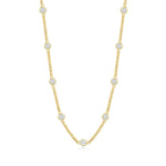 Gold necklace with bezel set clear stones on a white background