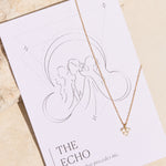 Necklace with a moon stone triangle pendant on a 'The Echo' affirmation card against a beige background