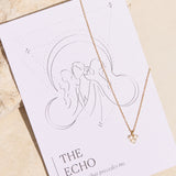 Necklace with a moon stone triangle pendant on a 'The Echo' affirmation card against a beige background