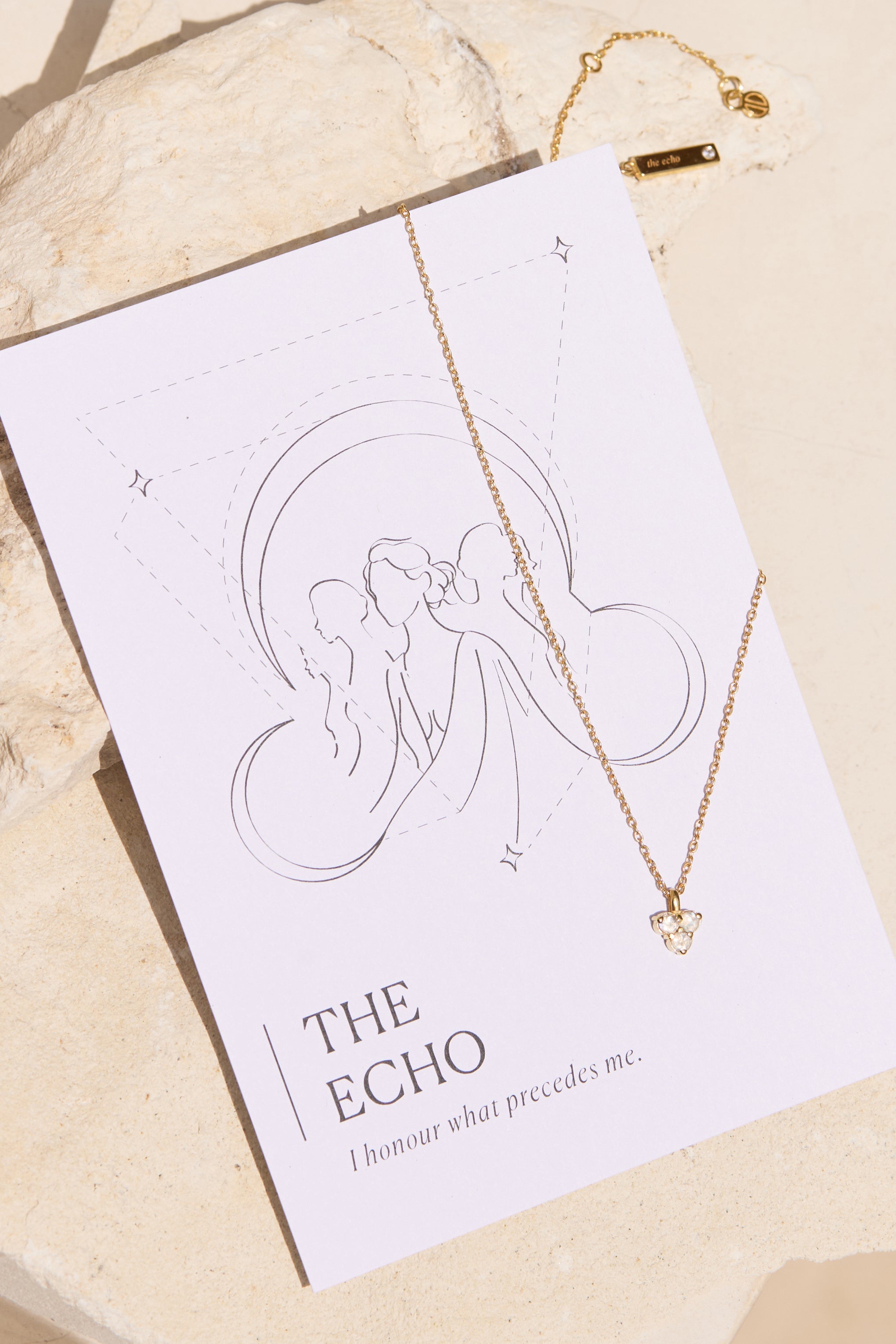 Necklace with a moon stone triangle pendant on a 'The Echo' affirmation card against a beige background