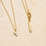 Gold necklace with moon stone pendant on a beige background