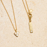 Gold necklace with moon stone pendant on a beige background