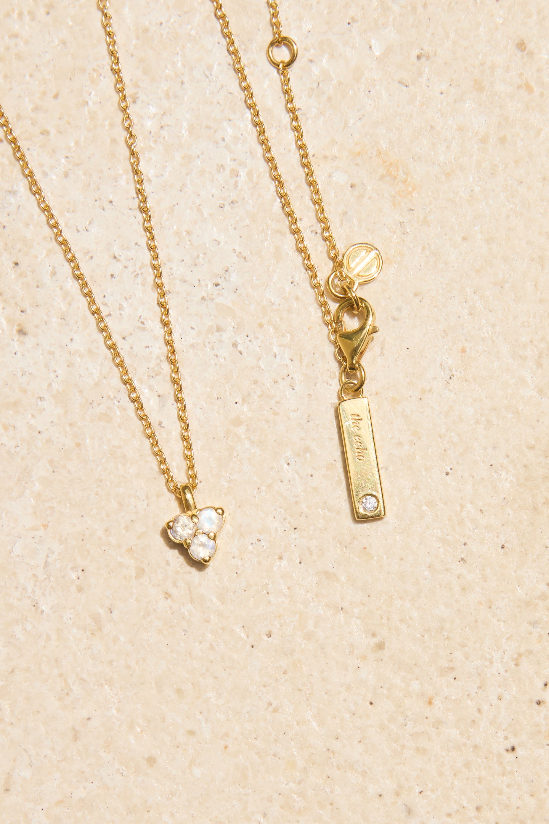 Gold necklace with moon stone pendant on a beige background