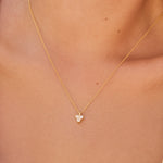 Gold necklace with a triangle-shaped moon stone pendant on a person's neck