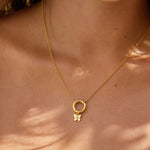 Close-up of a gold necklace with a small butterfly pendant on a person's neck.