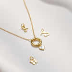 Gold necklace with various charm pendants on a white surface