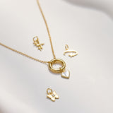 Gold necklace with various charm pendants on a white surface