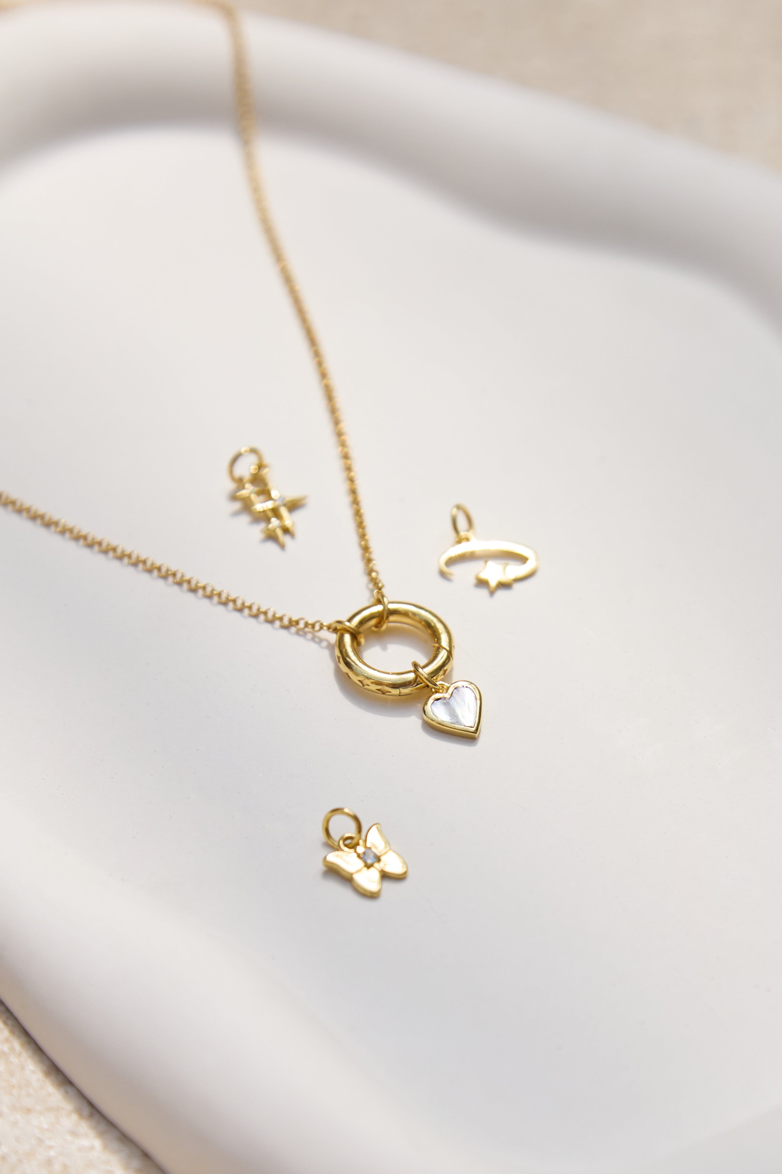 Gold necklace with various charm pendants on a white surface