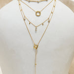 Layered gold necklaces on a white ceramic vase with a plain background
