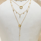 Layered gold necklaces on a white ceramic vase with a plain background