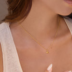 Gold necklace with a yellow citrine triangle pendant worn by a person