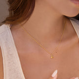Gold necklace with a yellow citrine triangle pendant worn by a person