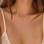 Woman wearing a delicate gold necklace with a star pendant and clear stone drops.