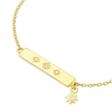 Gold bar bracelet with star-shaped symbols and charm on a white background